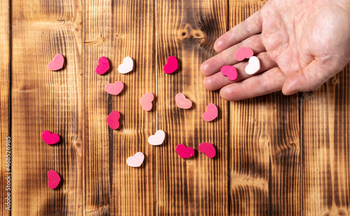 Red and pink hearts scattered from the hand on a wooden