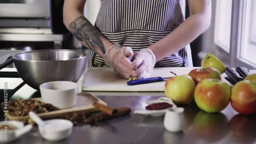 Female cook cutting apples in gloves on kitchen board, putting it into bowl, closeup hands shot Female cook cutting apples in gloves on kitchen board, putting it into bowl, closeup hands shot