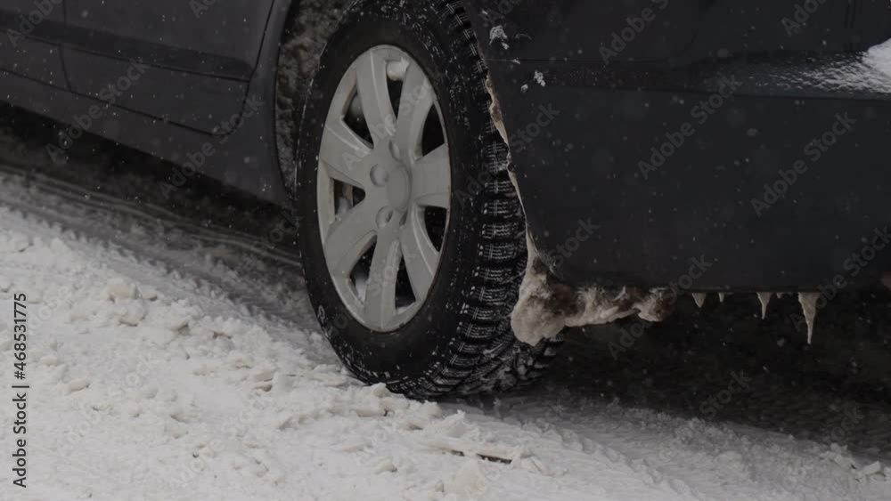 Car is driving on a snowcovered road in winter city. Smoke gases from