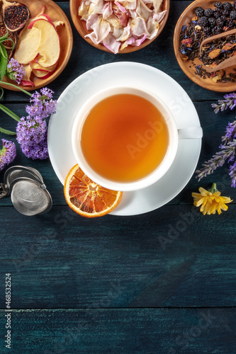 Tea with dry fruit and flowers, shot from the top on a dark rustic wooden background with a place for text