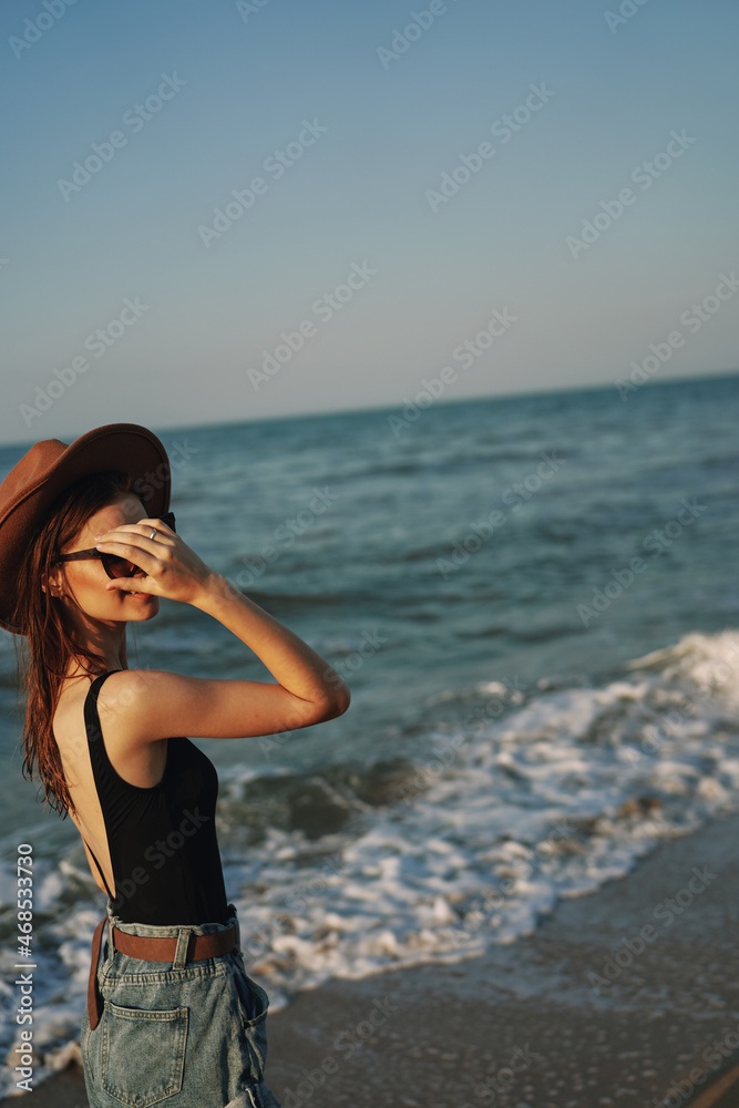 cheerful woman in sunglasses and a hat by the ocean walk summer