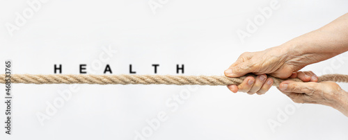 Health concept with wrinkled hands pull the rope towards themselves with text Health.