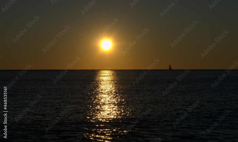 Sunset on the sea, sailboat on the horizon