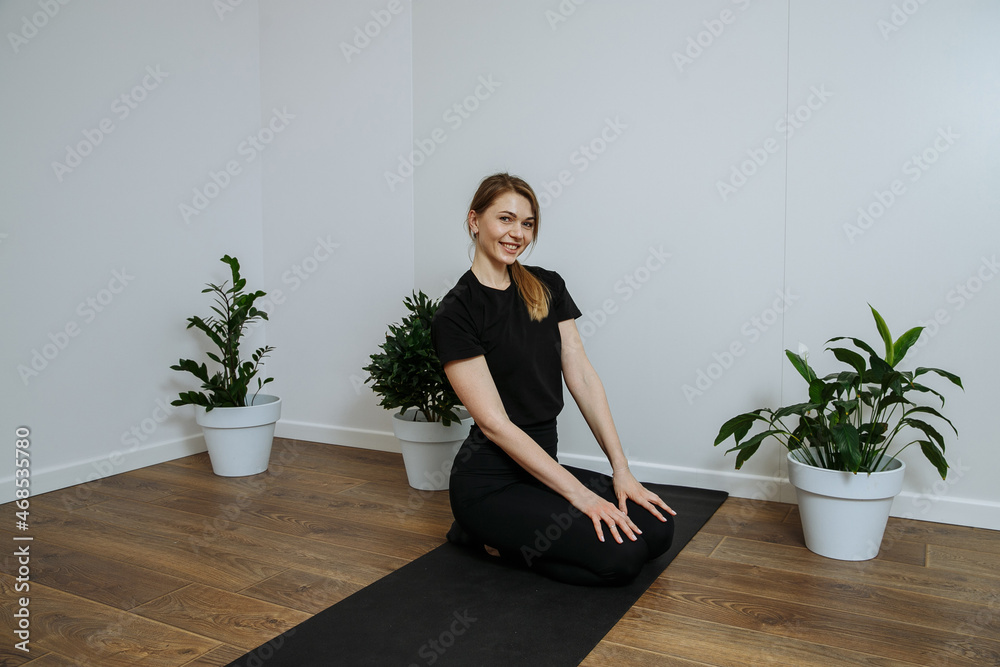 yoga trainer in black t-shirt works out on the mat