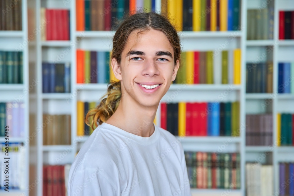 Portrait of a smiling teenage boy looking at the camera in the library. Portrait of a smiling teenage boy looking at the camera in the library.