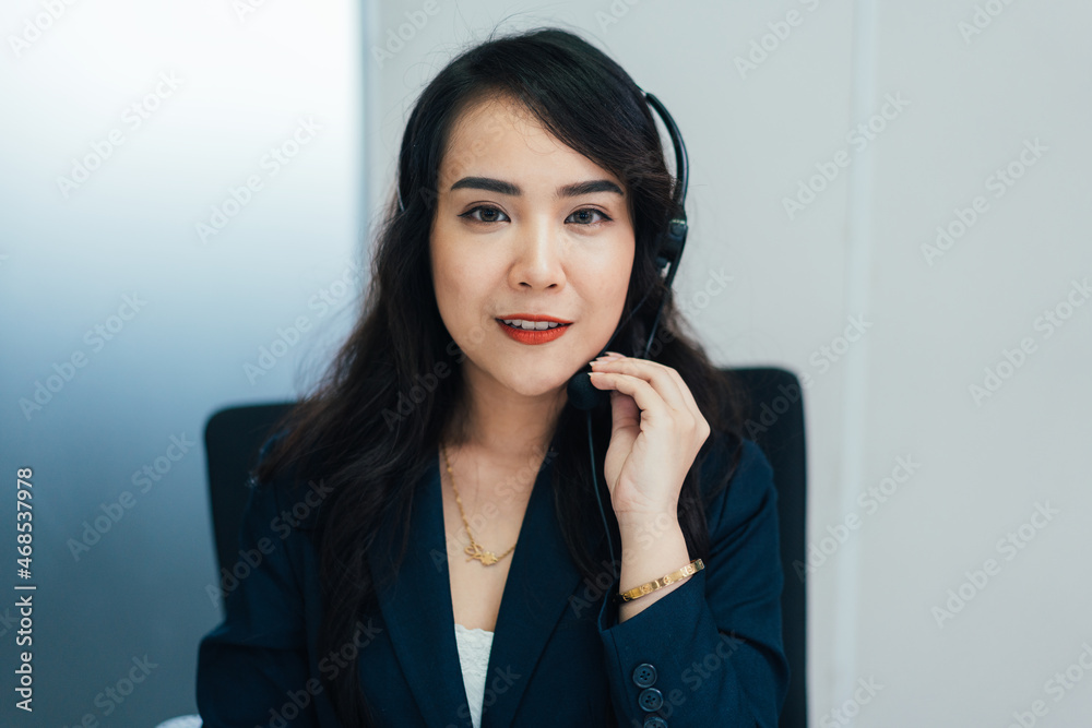 Portrait of Asian female telemarketer talking to customer at desk in the office looking at camera. POV of meeting at video conference call with client. service help desk. operator career Portrait of Asian female telemarketer talking to customer at desk in the office looking at camera. POV of meeting at video conference call with client. service help desk. operator career
