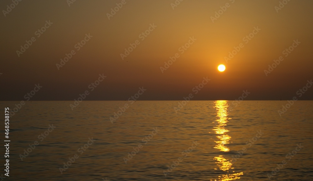 Orange sunset on the sea. The sun is above the horizon. Orange and brown shades
