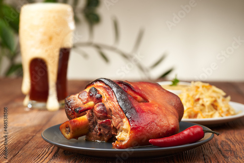 Hot eisbeine (pork knee)  with braised sauerkraut cabbage and craft beer on a dark and wooden background. Autumn food concept with copy space. Macro photo with shallow depth of field.