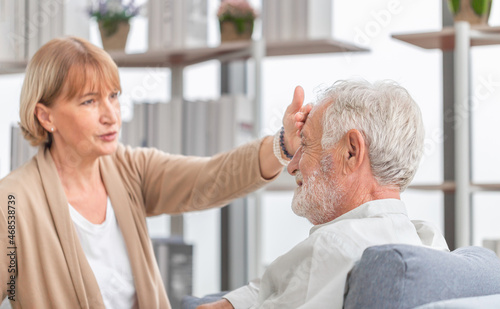 Woman checking fever on forehead by hand, Elderly woman touches the forehead of old husband, Senior couple and happy family concepts