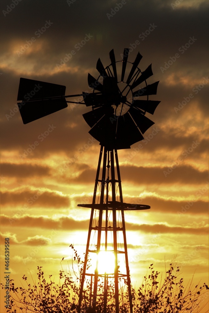 windmill at sunset with Strato Cumulus Clouds that's bright and colorful with a Windmill silhouette north of Hutchinson Kansas USA. windmill at sunset with Strato Cumulus Clouds that's bright and colorful with a Windmill silhouette north of Hutchinson Kansas USA.
