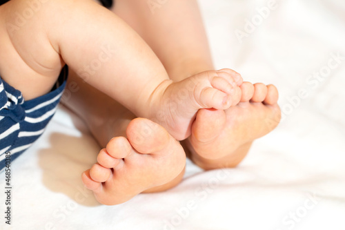 お母さんと赤ちゃんの寝っ転がっている足 お母さんの足に赤ちゃんの足が乗っている