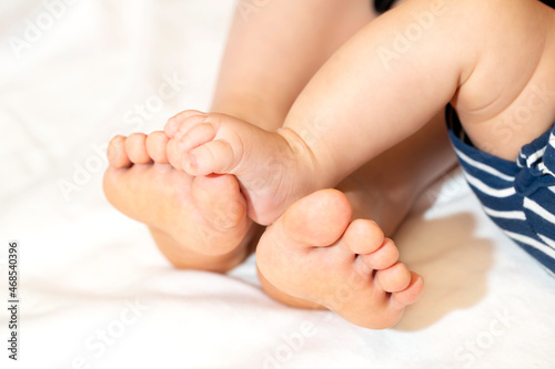 お母さんと赤ちゃんの寝っ転がっている足 お母さんの足に赤ちゃんの足が乗っている
