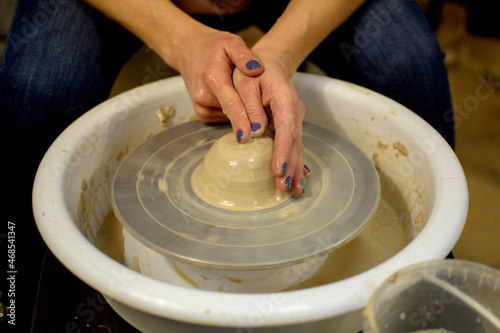 Master class on modeling of clay on a potter's. woman hands form by a clay pot. The potter works in a workshop