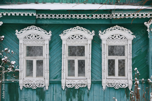 Ornamental windows with carved frames. Vintage wooden rural house in Dunilovo village, Ivanovo region, Russia. Building facade. Russian traditional national folk style in architecture. Landmark photo