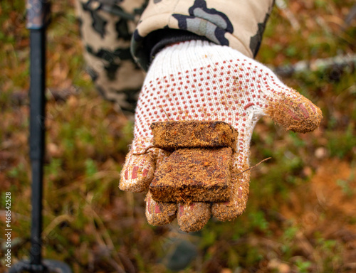 Man hands keep old iron fragments, clean them from dirt, clay, land and rust, after searching and producing scrap metal in forest.