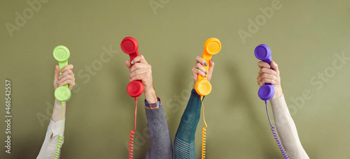 Foto Group of people holding different colourful landline phone receivers