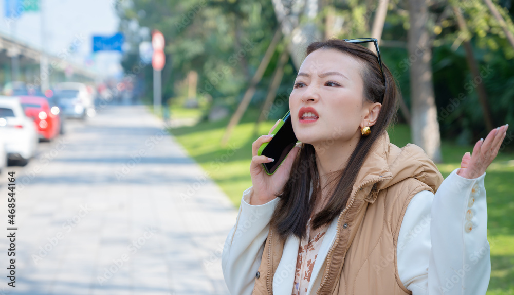 Portrait of pretty Chinese Asian young woman on street has mobile cell phone conversation holds near ear. Angry misunderstanding emotions from call bad news mouth opened, scammers calling shouting Portrait of pretty Chinese Asian young woman on street has mobile cell phone conversation holds near ear. Angry misunderstanding emotions from call bad news mouth opened, scammers calling shouting