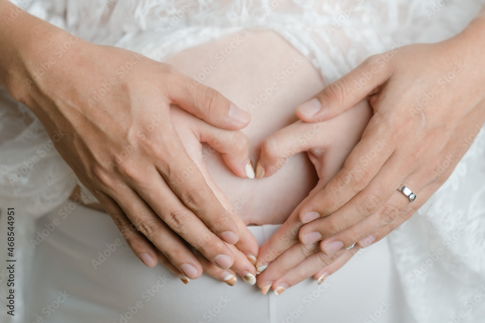 Close up of a cute pregnant belly.Cropped image of beautiful pregnant woman and her handsome husband hugging the tummy Close up of a cute pregnant belly.Cropped image of beautiful pregnant woman and her handsome husband hugging the tummy