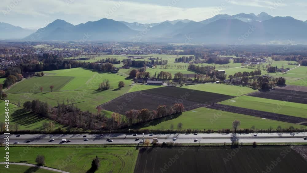 Aerial Drone flying left to right showing multiple cars on a highway going both directions in the foreground and the beautiful blue mountains in the background with it's great nature.