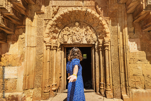 Follow me to the tourist attractions of Armenia. Happy woman traveler in blue dress at the entrance to famous Noravank monastery © EdNurg