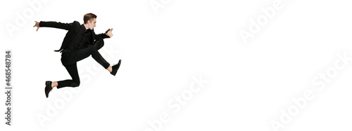 Young man in black business suit dancing isolated on white background. Art, motion, action, flexibility, inspiration concept. photo