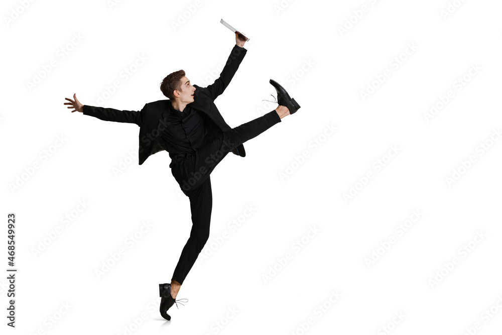Full-length portriat of young man in black business suit dancing isolated on white background. Art, motion, action