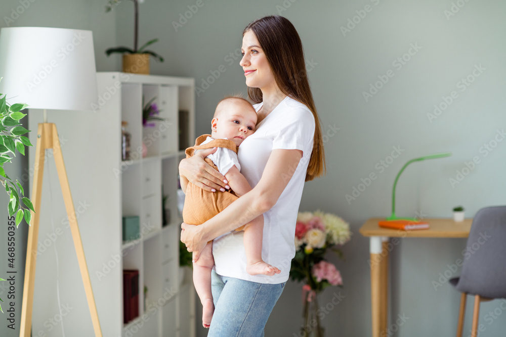 Photo of adorable charming lady wear white t-shirt holding hands arms baby inside indoors house room Photo of adorable charming lady wear white t-shirt holding hands arms baby inside indoors house room