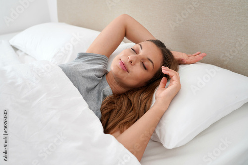 Good sleep. Relaxed young woman lying sleeping in comfortable bed in the morning