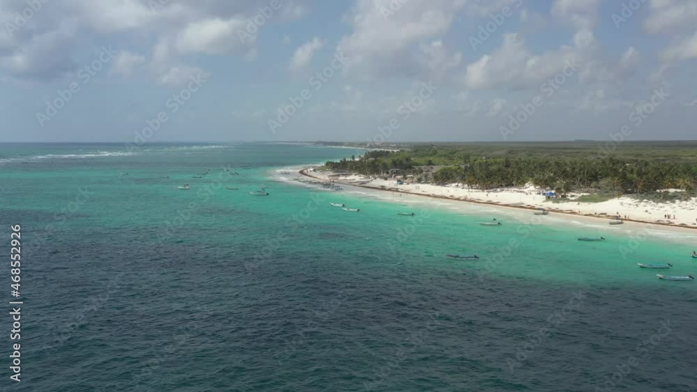 Aerial flyover turquoise water of Riviera Maya in Tulum during sunny day - Golden sandy beach, many anchored boats in summer in Mexico Aerial flyover turquoise water of Riviera Maya in Tulum during sunny day - Golden sandy beach, many anchored boats in summer in Mexico