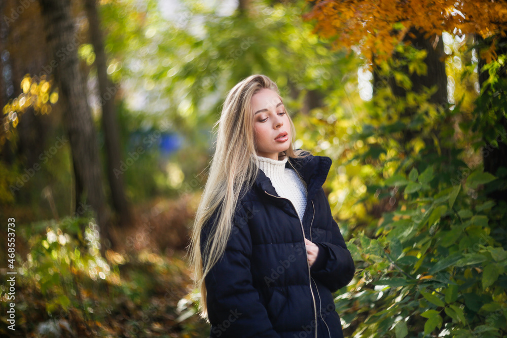 beautiful fashionable young girl in a black jacket and a sweater in the park among the trees, caucasian girl with beautiful long hair and full lips beautiful fashionable young girl in a black jacket and a sweater in the park among the trees, caucasian girl with beautiful long hair and full lips