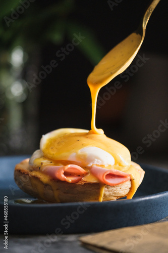 Foto egg Benedict with hollandaise sauce on dark blue plate on table in kitchen