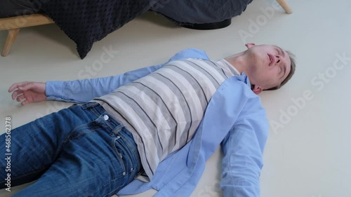 Epileptic seizure. A man struggles in convulsions while lying on the floor photo