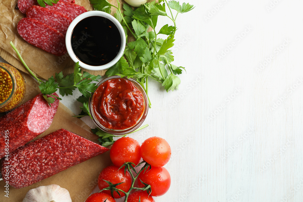 Сoncept of tasty food with salami sausage on white wooden background Сoncept of tasty food with salami sausage on white wooden background