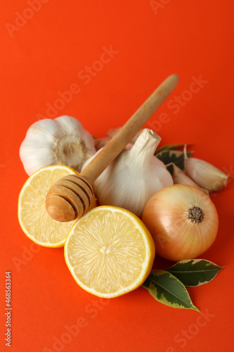 Concept of treatment colds with honey and garlic on orange background