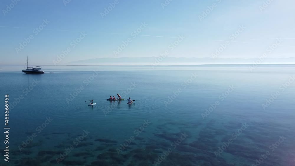 Aerial view video of active family on SUP stand up paddle vacation. Parents and children enjoying summer vacation on paradise Mediterranean beach in Adriatic Sea, Silba, Croatia. Aerial view video of active family on SUP stand up paddle vacation. Parents and children enjoying summer vacation on paradise Mediterranean beach in Adriatic Sea, Silba, Croatia.