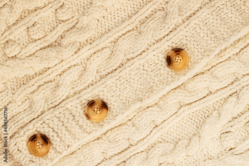 Handmade knitwear, pullover with buttons, knitted light texture, background, copy space Handmade knitwear, pullover with buttons, knitted light texture, background, copy space