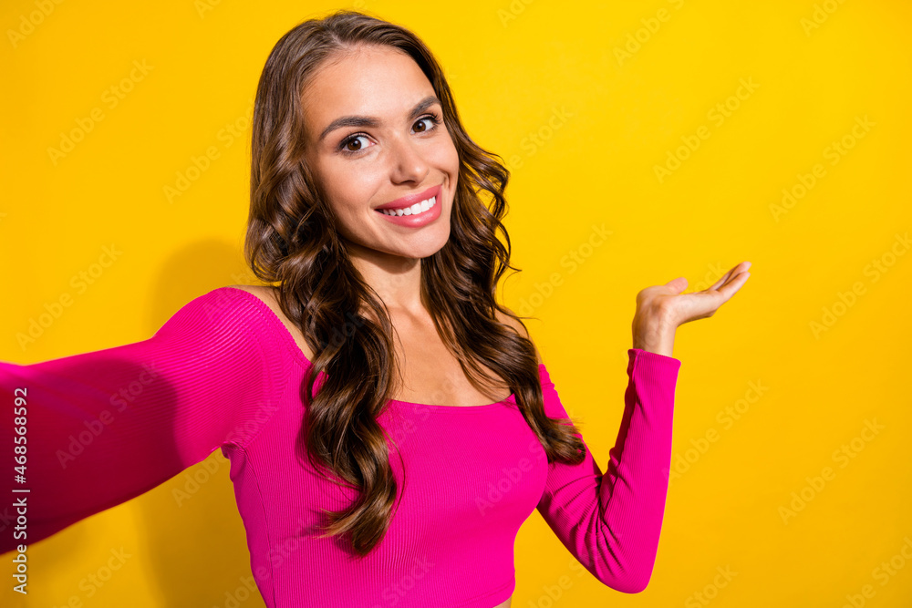 Self-portrait of attractive cheerful girl holding on palm copy space isolated over vibrant yellow color background Self-portrait of attractive cheerful girl holding on palm copy space isolated over vibrant yellow color background