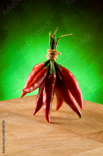 Bunch of red chilli peppers sitting on a timber bench