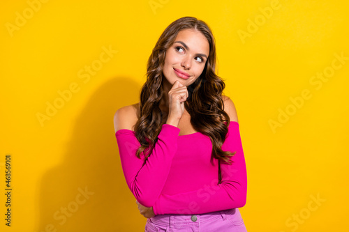 Portrait of attractive pensive brainy foxy cheerful wavy-haired girl thinking copy space isolated over vibrant yellow color background