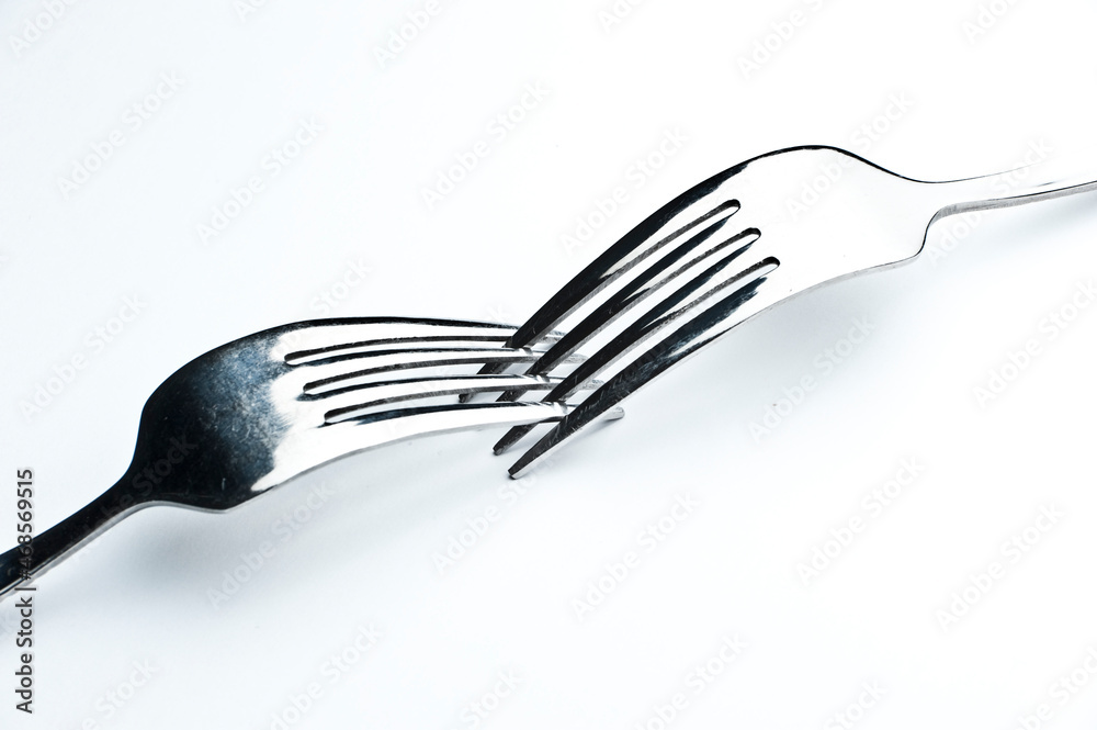 Two forks interwoven isolated on white background with subtle shadow Two forks interwoven isolated on white background with subtle shadow