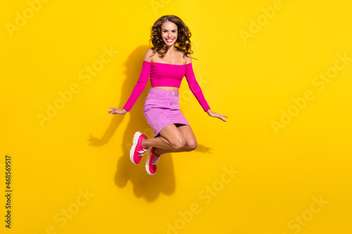Fototapeta Naklejka Na Ścianę i Meble -  Full length body size view of attractive cheerful girl jumping having fun isolated over vibrant yellow color background