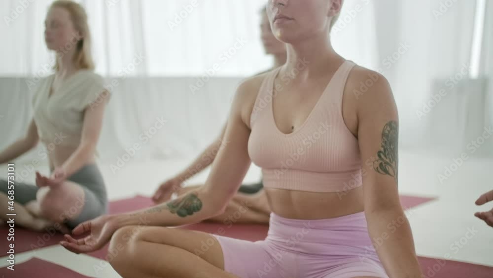 Group of Young Women and Man Practicing Yoga Zen Meditation Pose Sitting on Yoga Mats in Bright Class. Young Sporty People on Crossed Legs on the Floor and do Namaste Pose in Gym Studio. Group of Young Women and Man Practicing Yoga Zen Meditation Pose Sitting on Yoga Mats in Bright Class. Young Sporty People on Crossed Legs on the Floor and do Namaste Pose in Gym Studio.