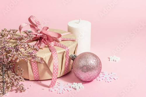 Christmas or New Year gift concept in pink tones. Wrapper box, tied bow, flowers, and festive toy