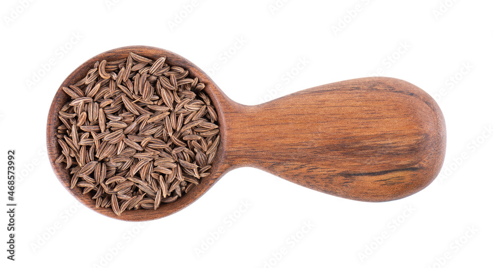 Cumin seeds in wooden spoon, isolated on white background. Dry caraway seeds. Top view. Cumin seeds in wooden spoon, isolated on white background. Dry caraway seeds. Top view.