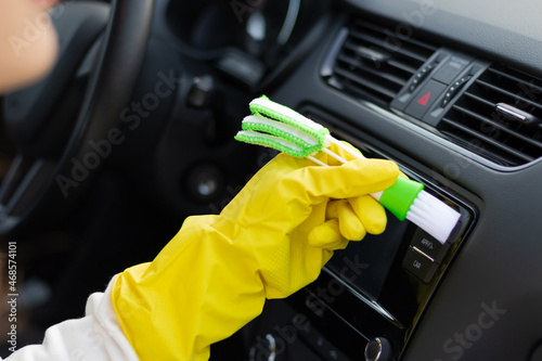 Valokuva A hand in yellow rubber gloves wipes the dashboard of a car from dust with a special brush on a bright autumn day