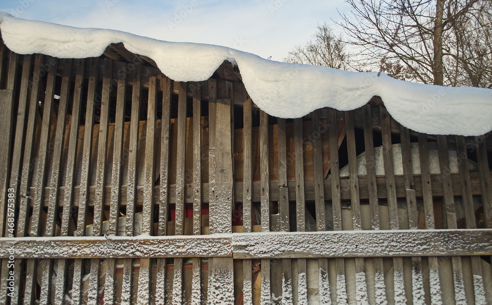 Fototapeta premium A snowy wooden shed on a sunny winter day. 