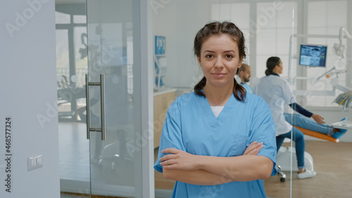 Portrait of dentistry assistant looking at camera standing at stomatology clinic. Caucasian woman with nurse occupation working in dental office wearing medical uniform for teethcare