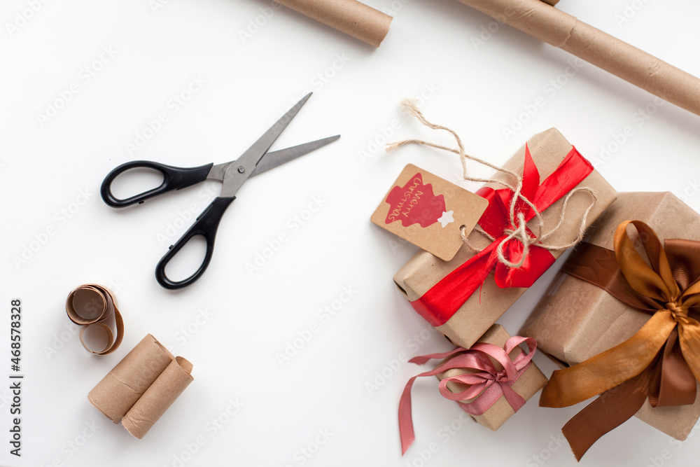 Wrapping christmas gifts with eco reusable materials - scissors, craft paper and ribbons Wrapping christmas gifts with eco reusable materials - scissors, craft paper and ribbons