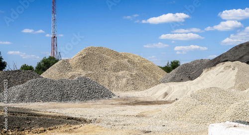 Large hills and piles of sand, gravel, crushed stone of white, gray and black color.