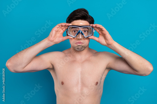 Photo of funky funny young man naked torso arms diving glasses bloated cheeks isolated blue color background